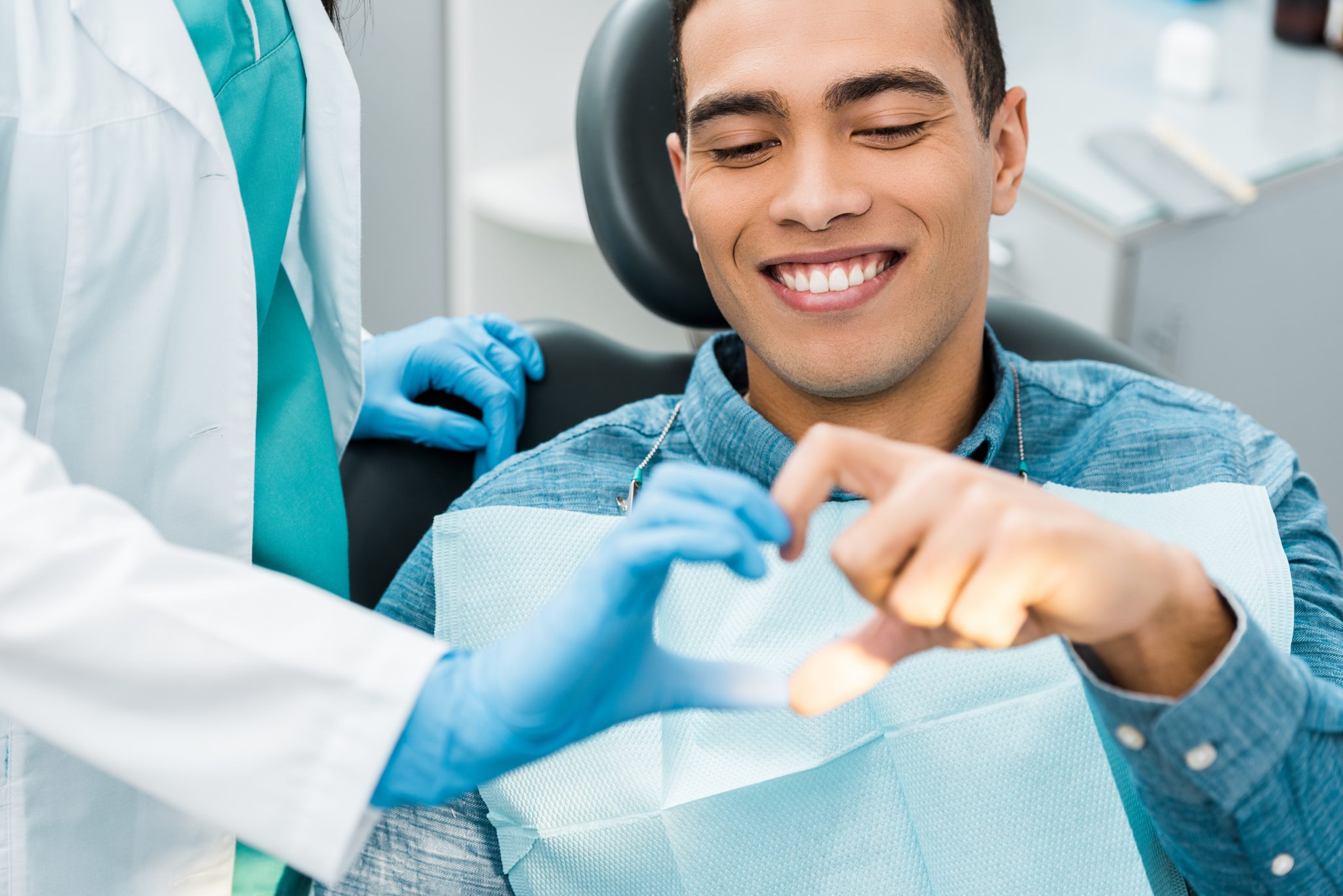 handsome african american man showing heart shape with female dentist
