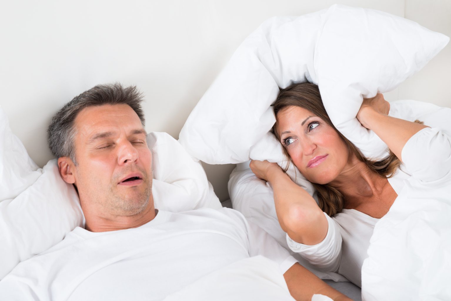 Angry woman trying to sleep with snoring man.