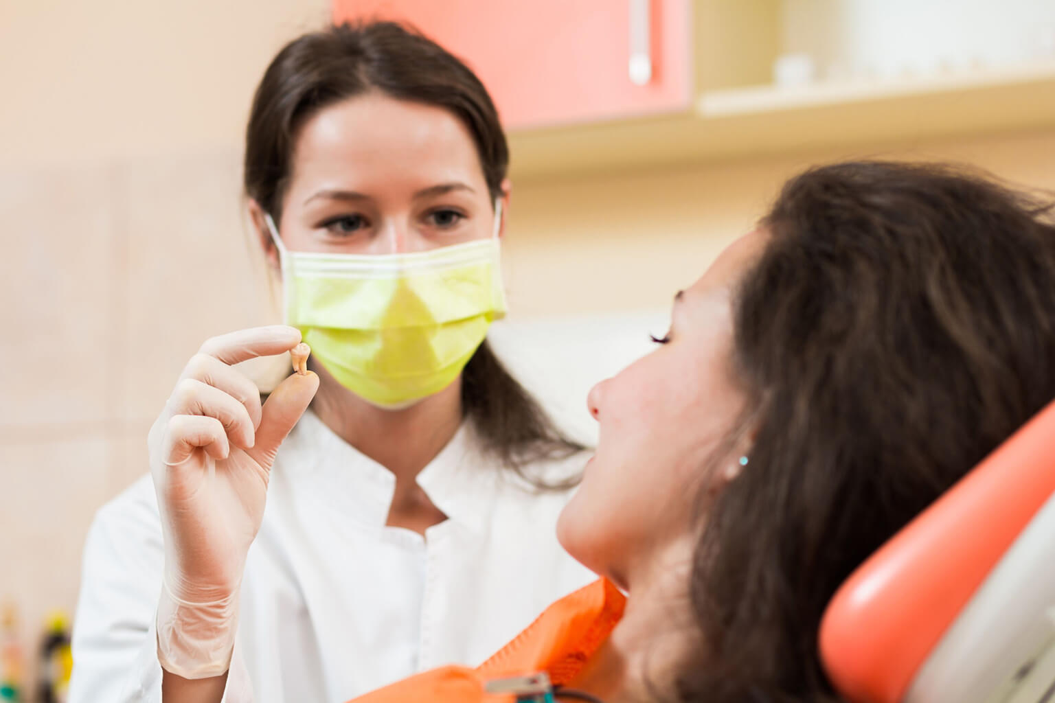 Dentist showing patient extracted tooth